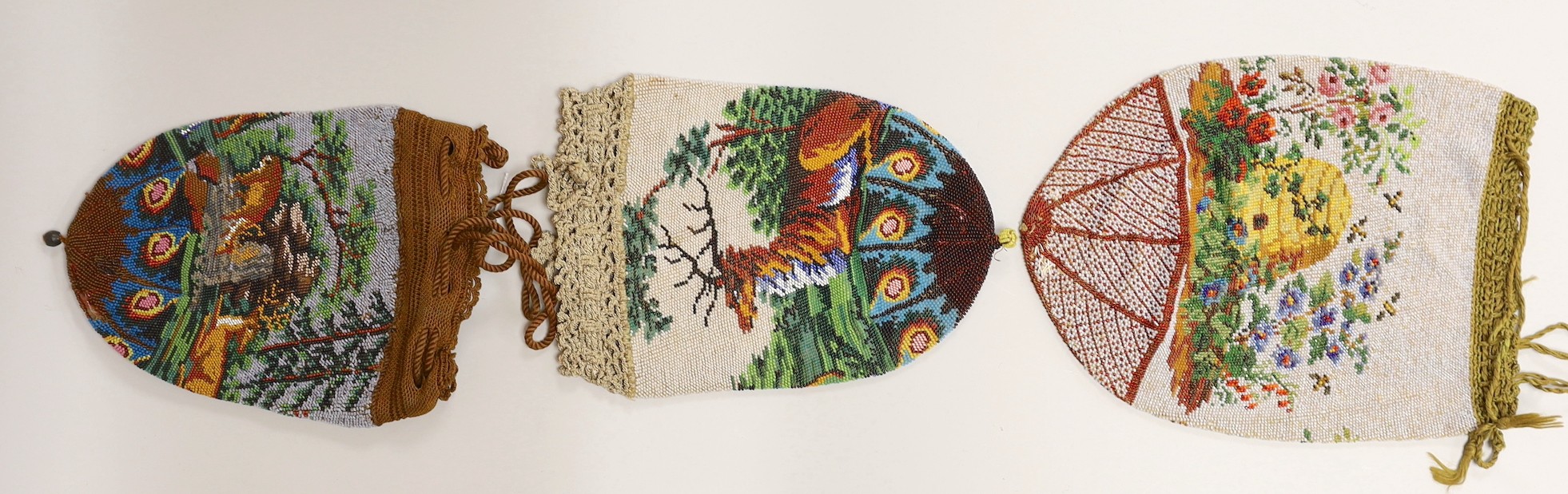 Two 19th century draw string beaded bags with hunting scenes, possibly American and a similar beaded bag depicting a bee hive in a garden.